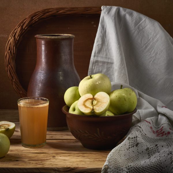 A rustic arrangement of apples, juice, and earthenware, evoking a cozy kitchen vibe.